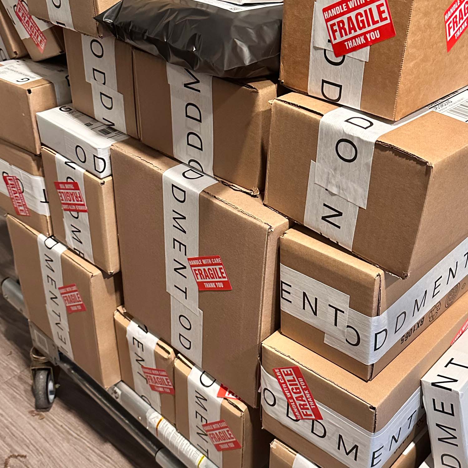 Stack of cardboard boxes with 'Fragile' and 'Oddment' labels on a cart.