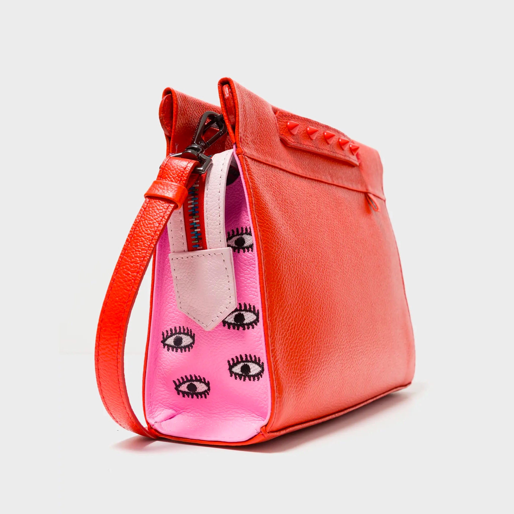 Angled view of Min & Mon's Vali Crossbody Small Fiesta Red and Bubblegum Pink Leather Bag - All Over Eyes Embroidery