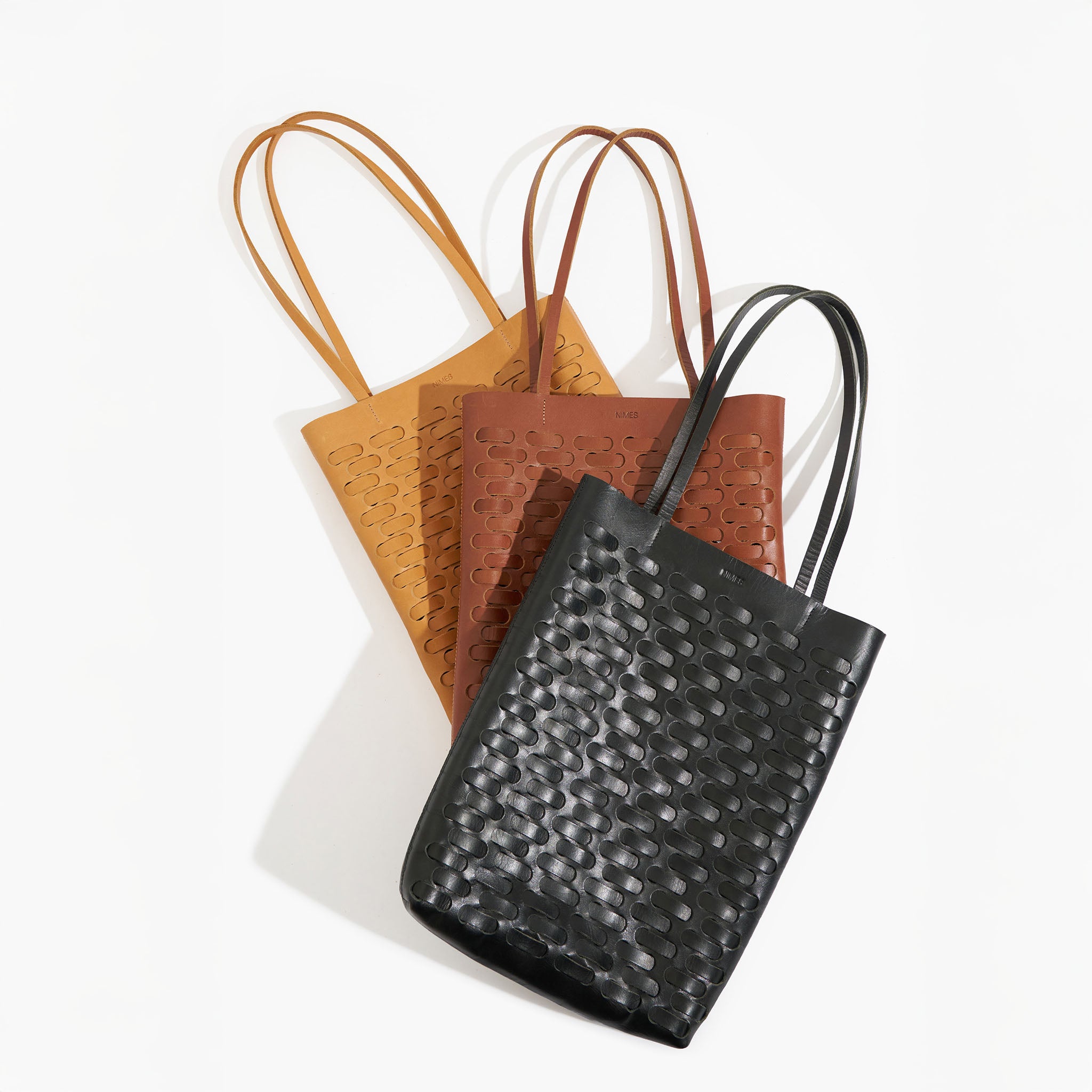 Three textured weave tote bags in black, brown, and orange on a white background
