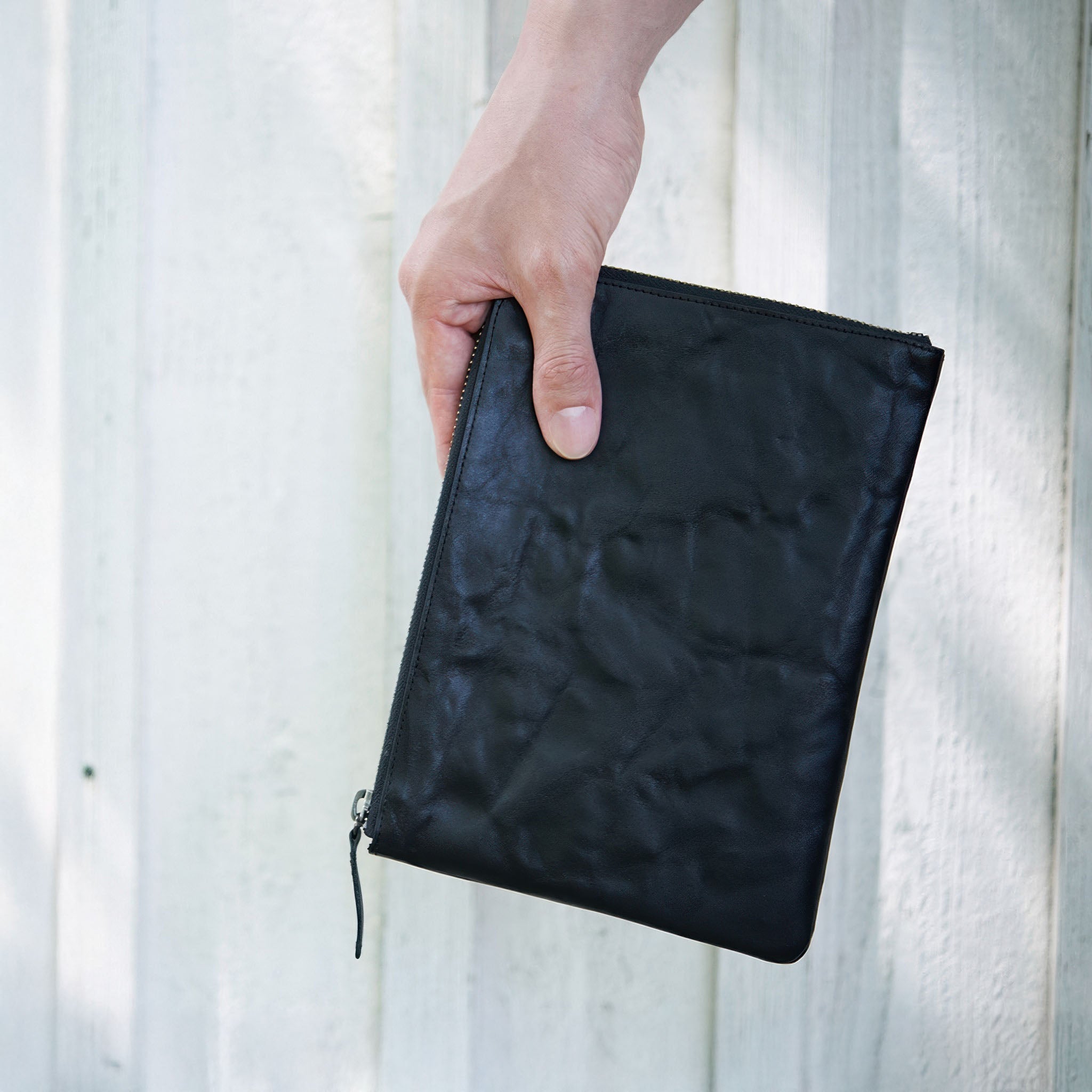 Hand holding hmny's black 10 mile bag against a light background