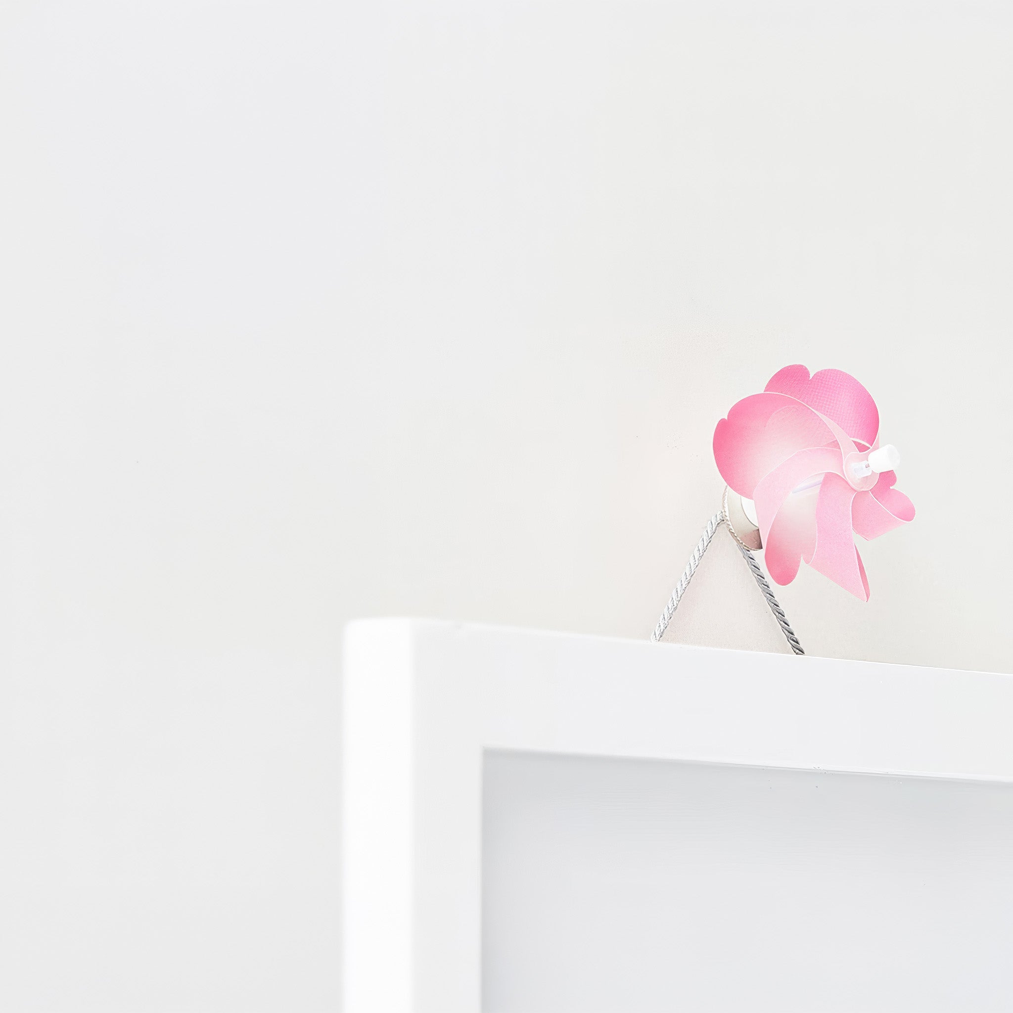 A cherry blossom pinwheel adorning a picture frame on a white background