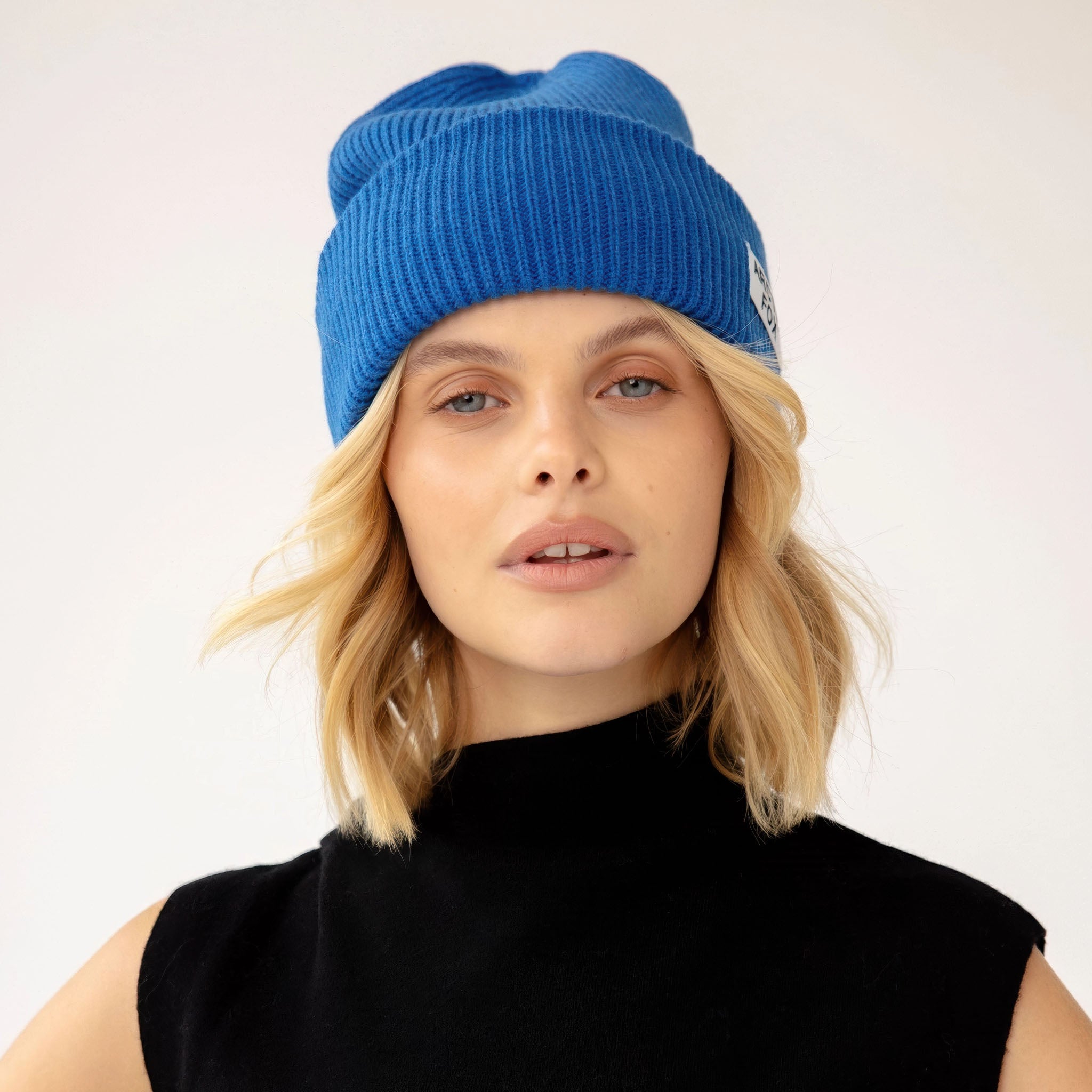 Model wearing a blue beanie with a white Arctic Fox logo on a light gray background