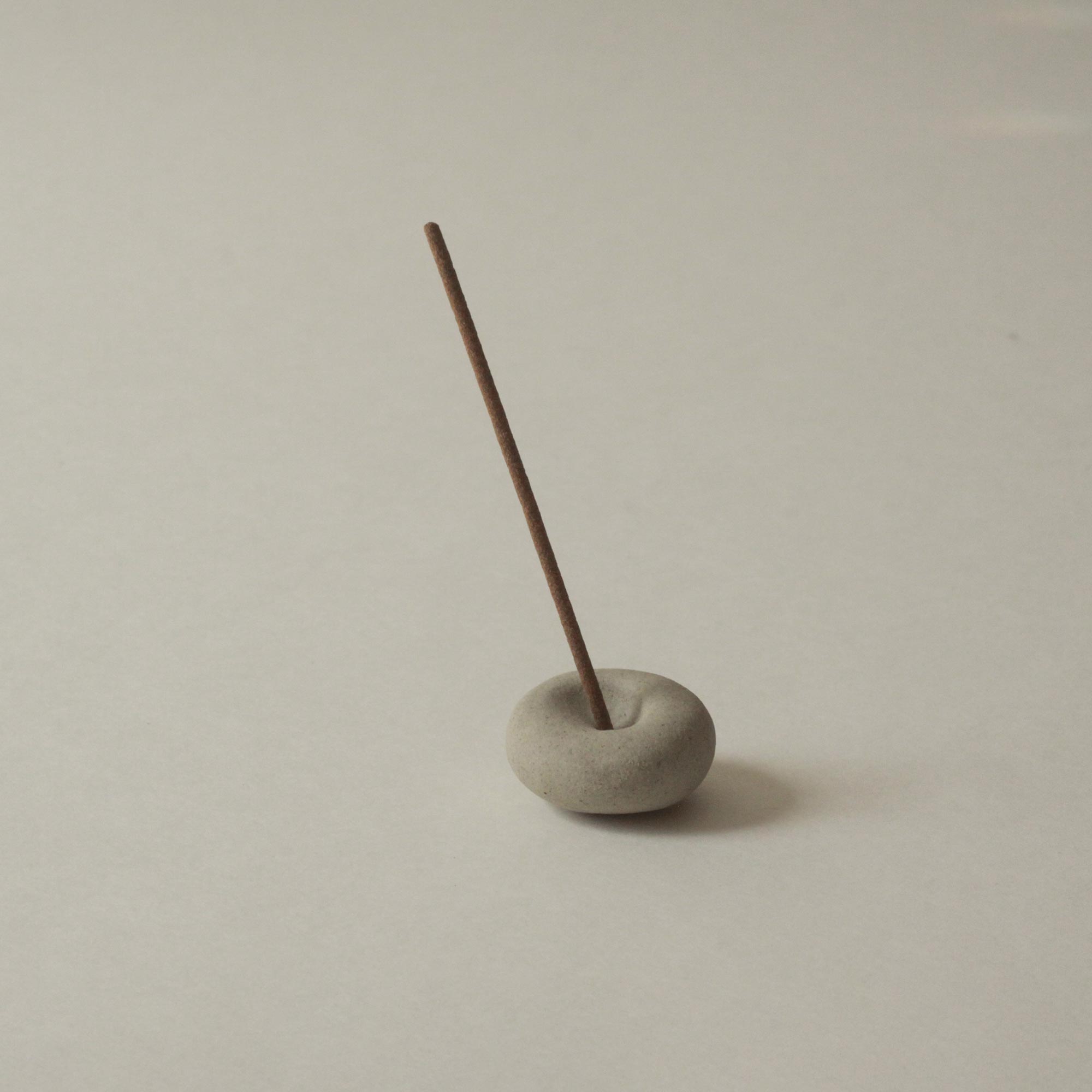 Incense stick in a mini light grey ceramic pebble incense holder