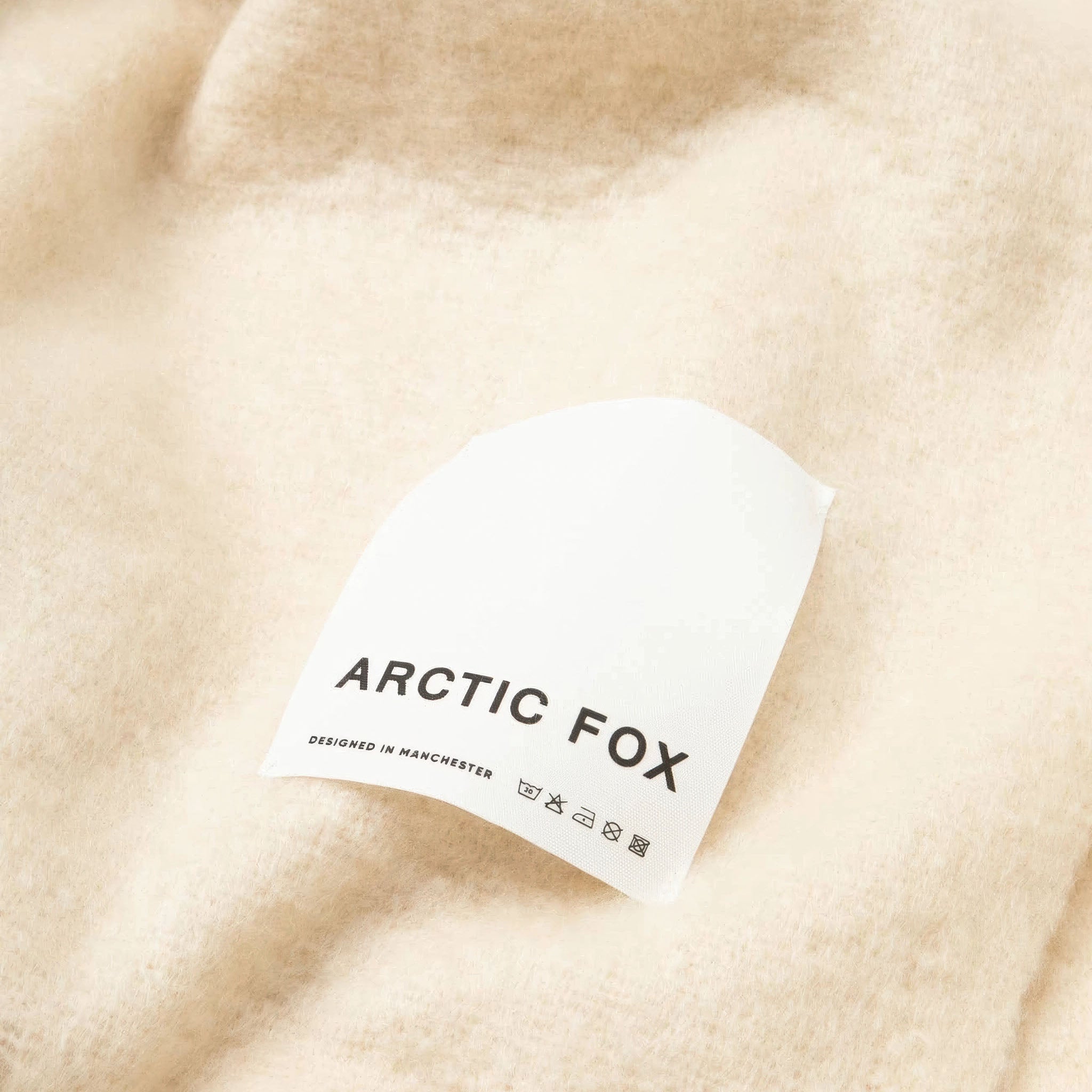 Close-up of the beige throw and white brand label Arctic Fox