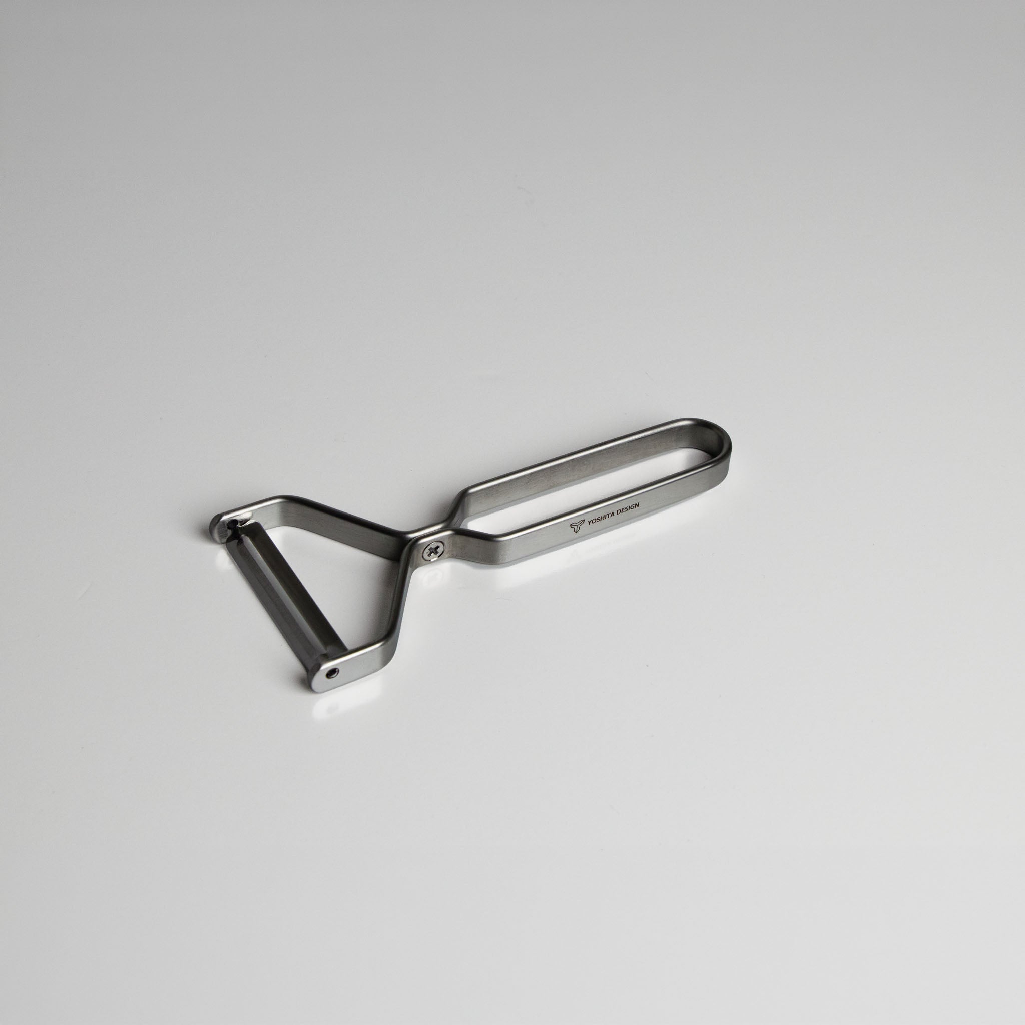 Yoshita stainless steel peeler on a light gray background
