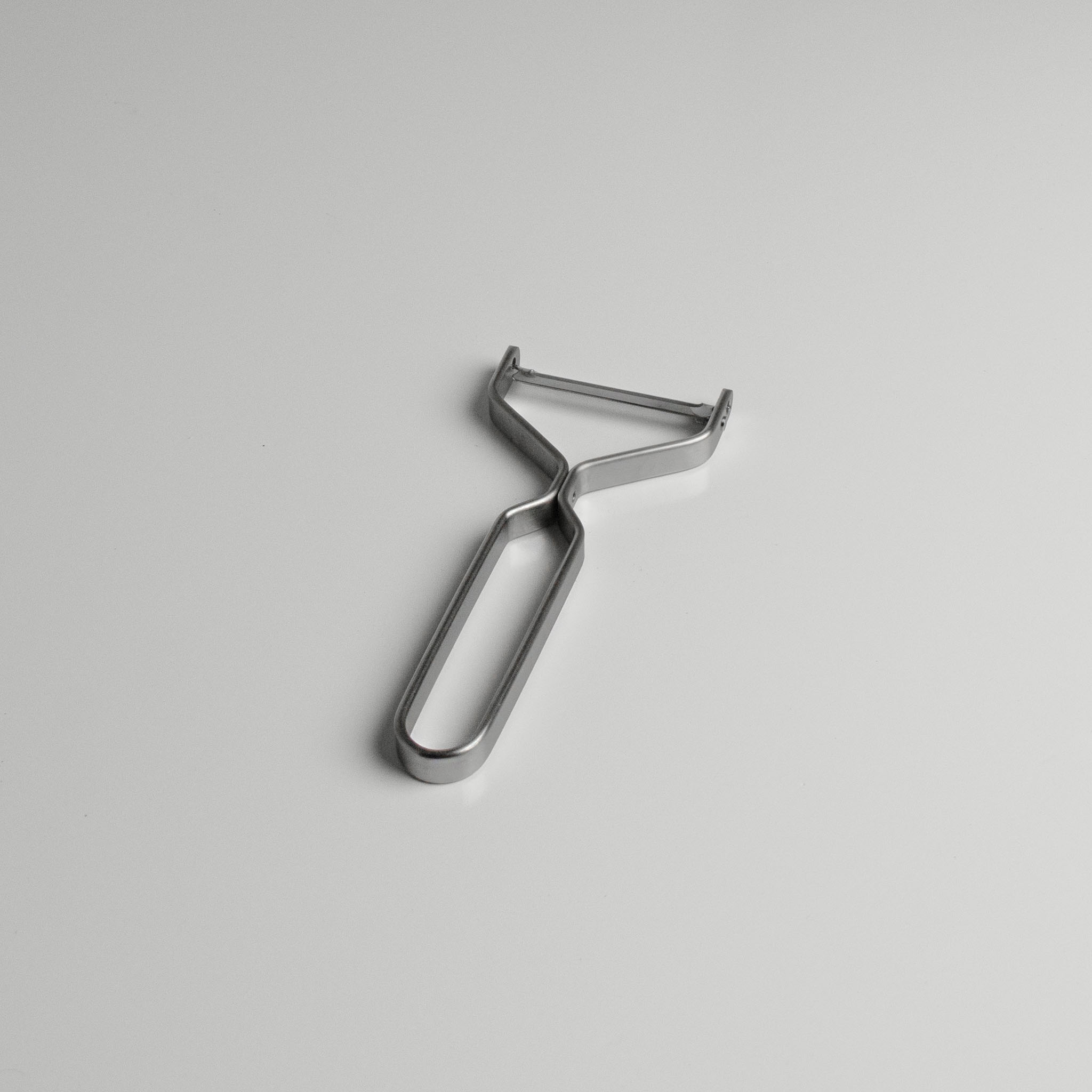 Yoshita stainless steel peeler on a light gray background