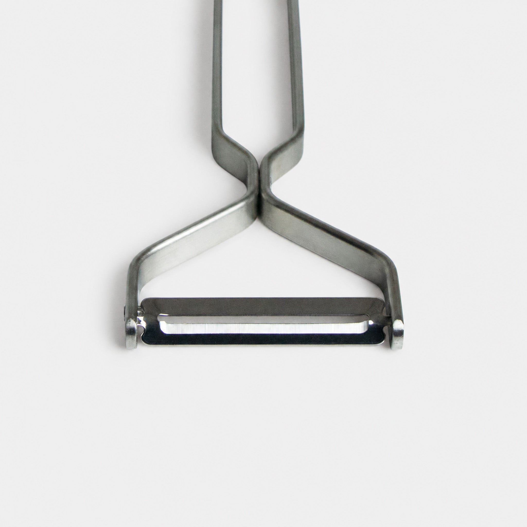 Close up of the Yoshita stainless steel peeler on a light gray background