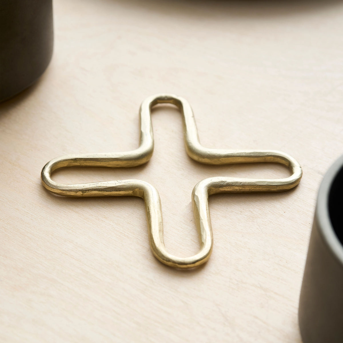 An angled close up view of the brass metal mini trivet set on a wood background