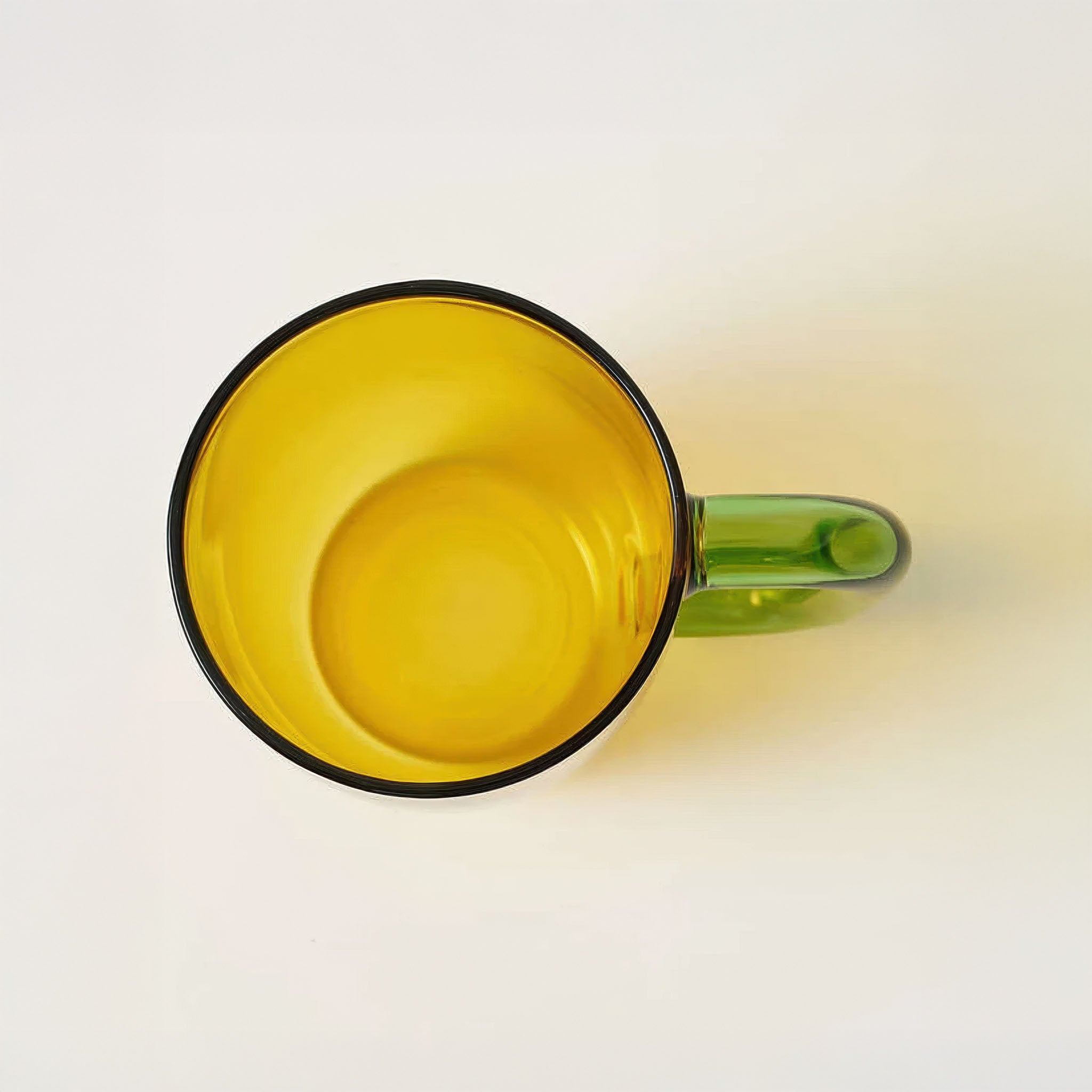 Top down view of yellow glass mug on a white background