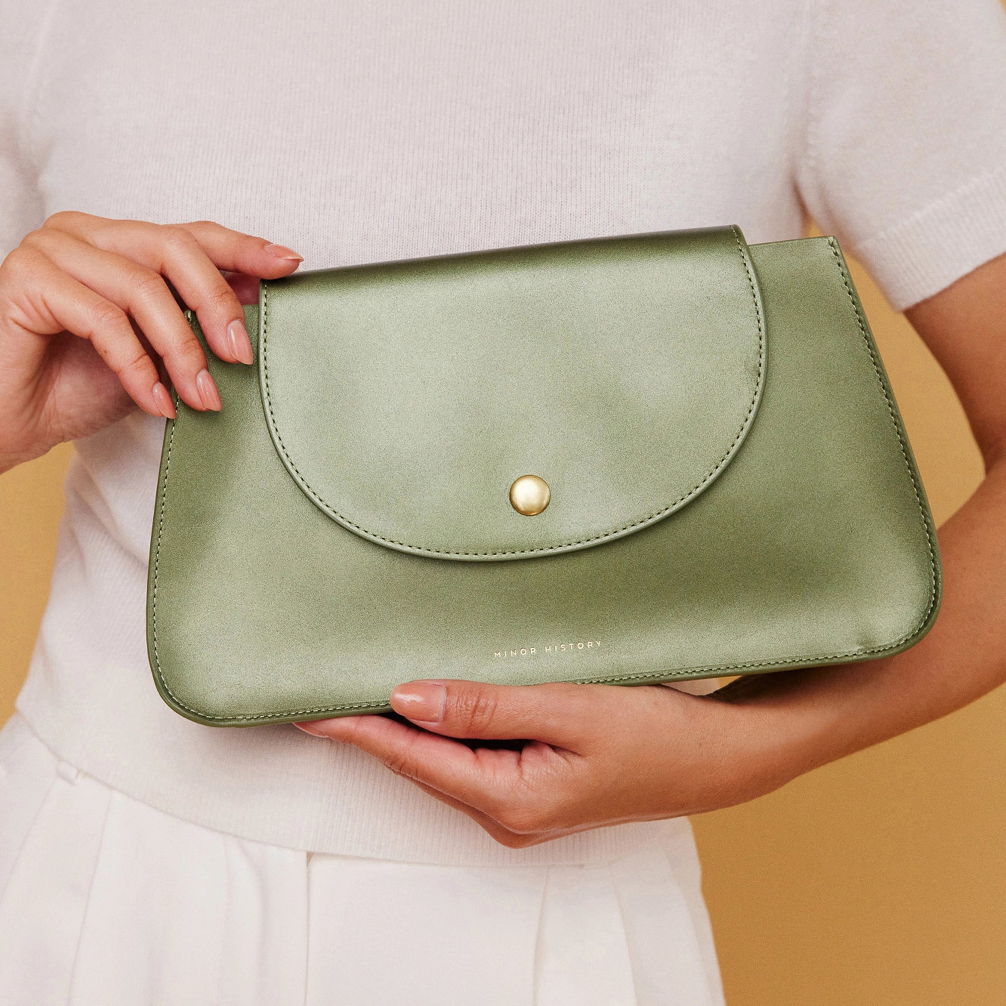 hand model holding Minor History's The Horizon Crossbody bag jade color