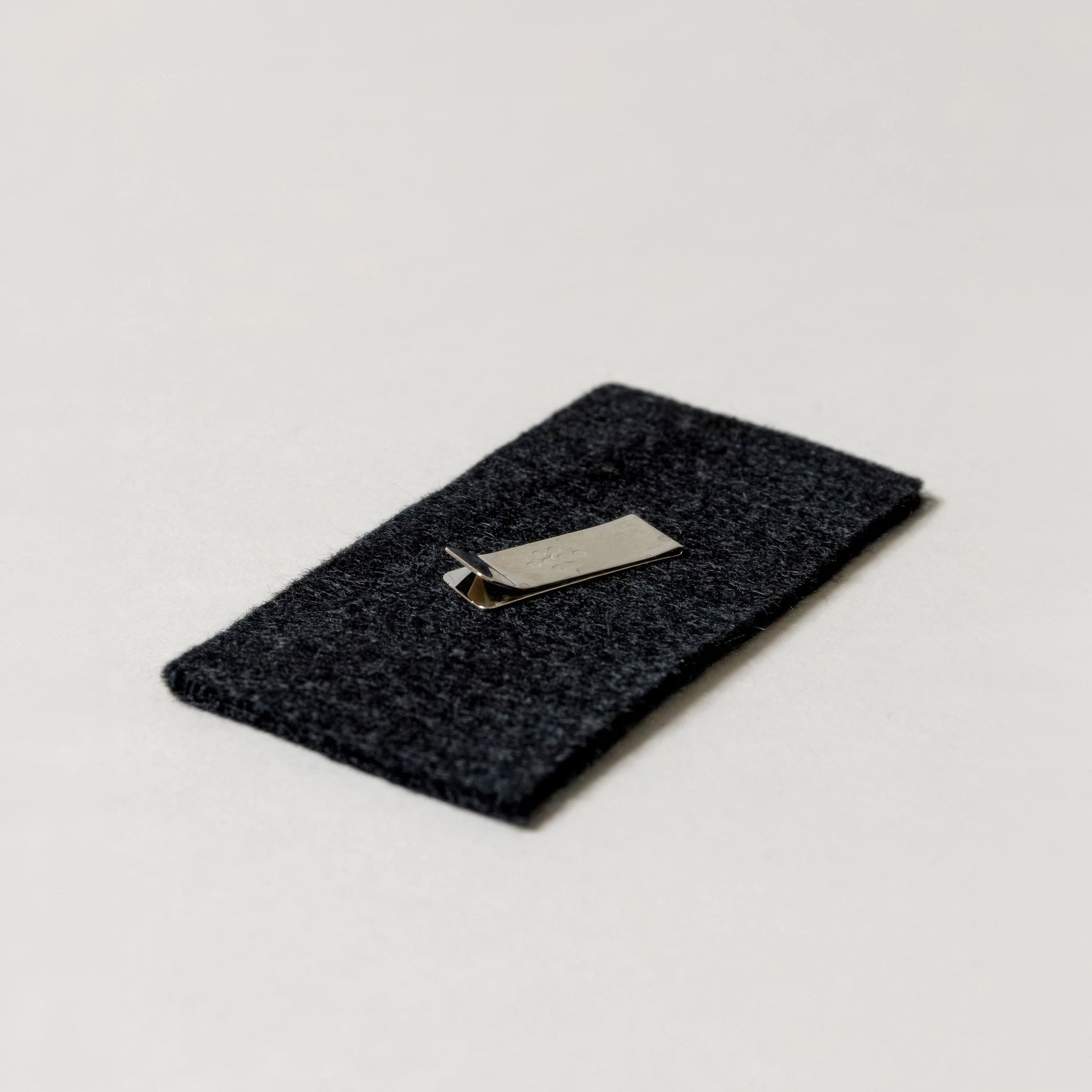 Dark gray felt with a silver clip on a light gray background