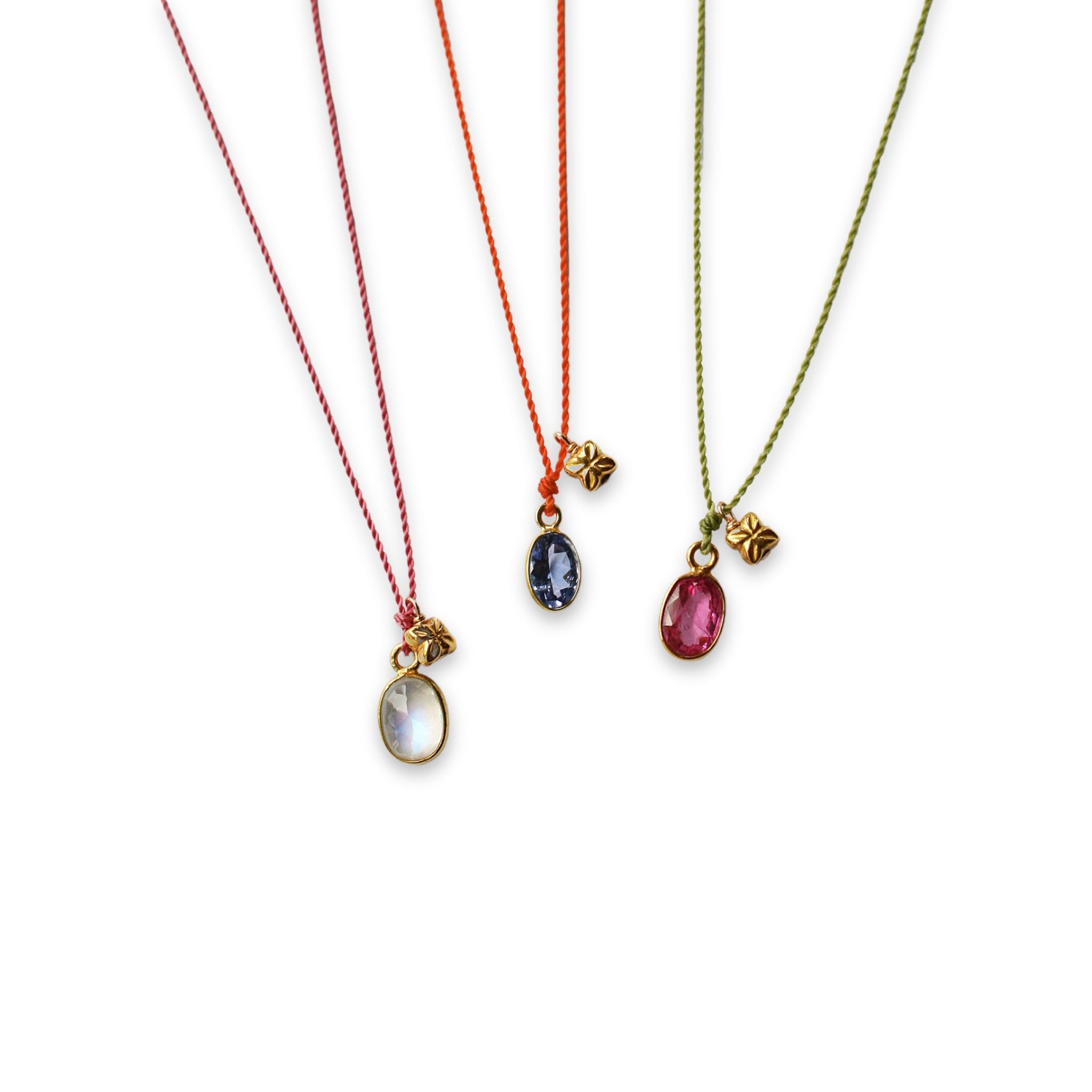 image partial of three see real flowers necklaces with blossom charm hanging next to each other