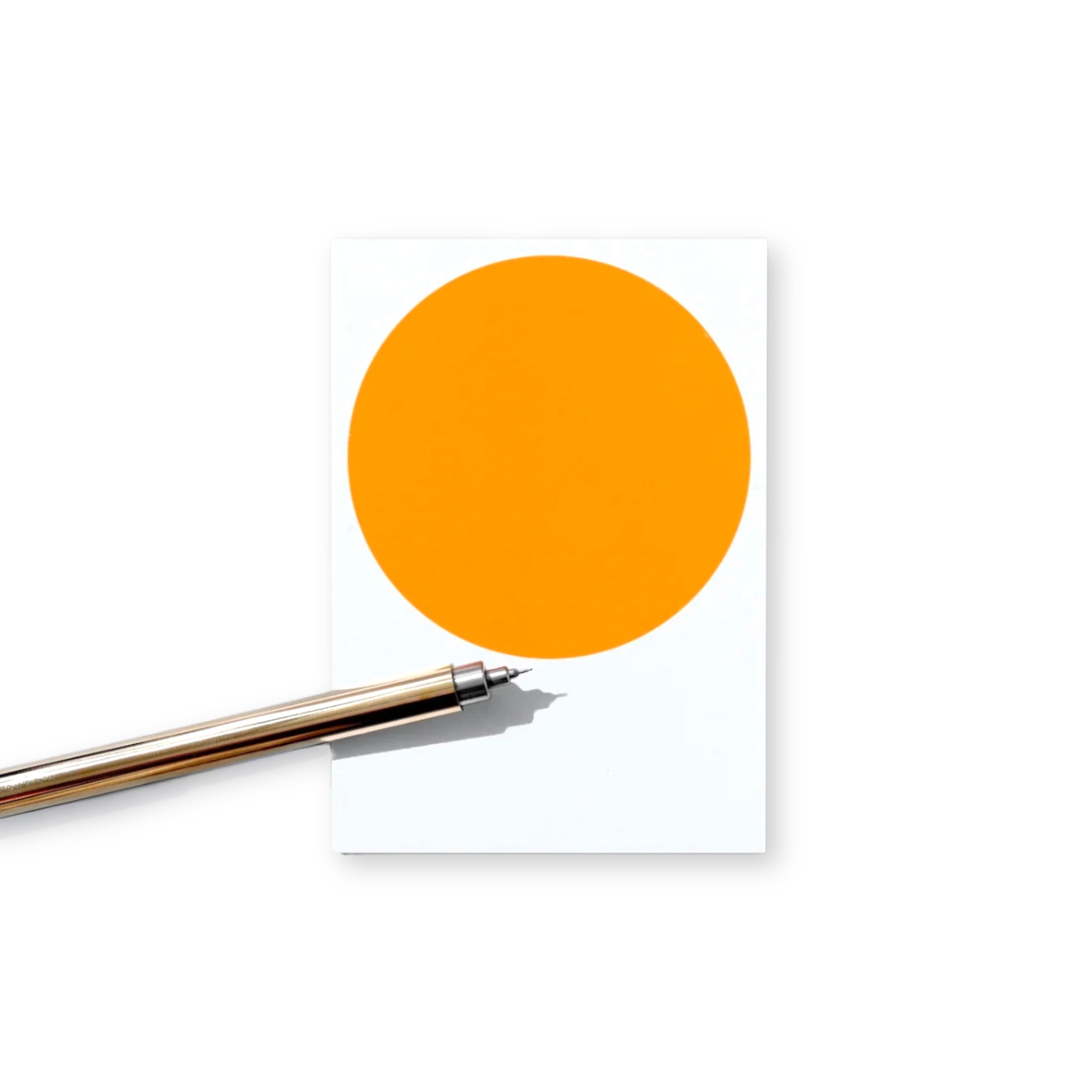 Orange circle on a white notebook with a pen