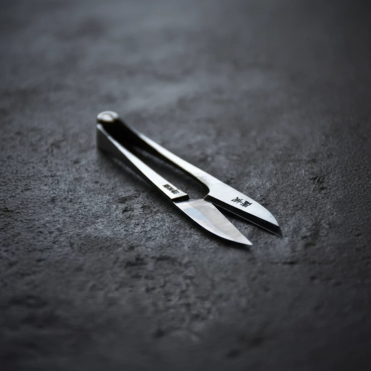 Pair of Terazaki Hamono Tsume Scissors on a dark gray surface