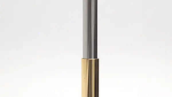 A close-up of a slim metallic pen that has a piston-like effect against a plain white background.