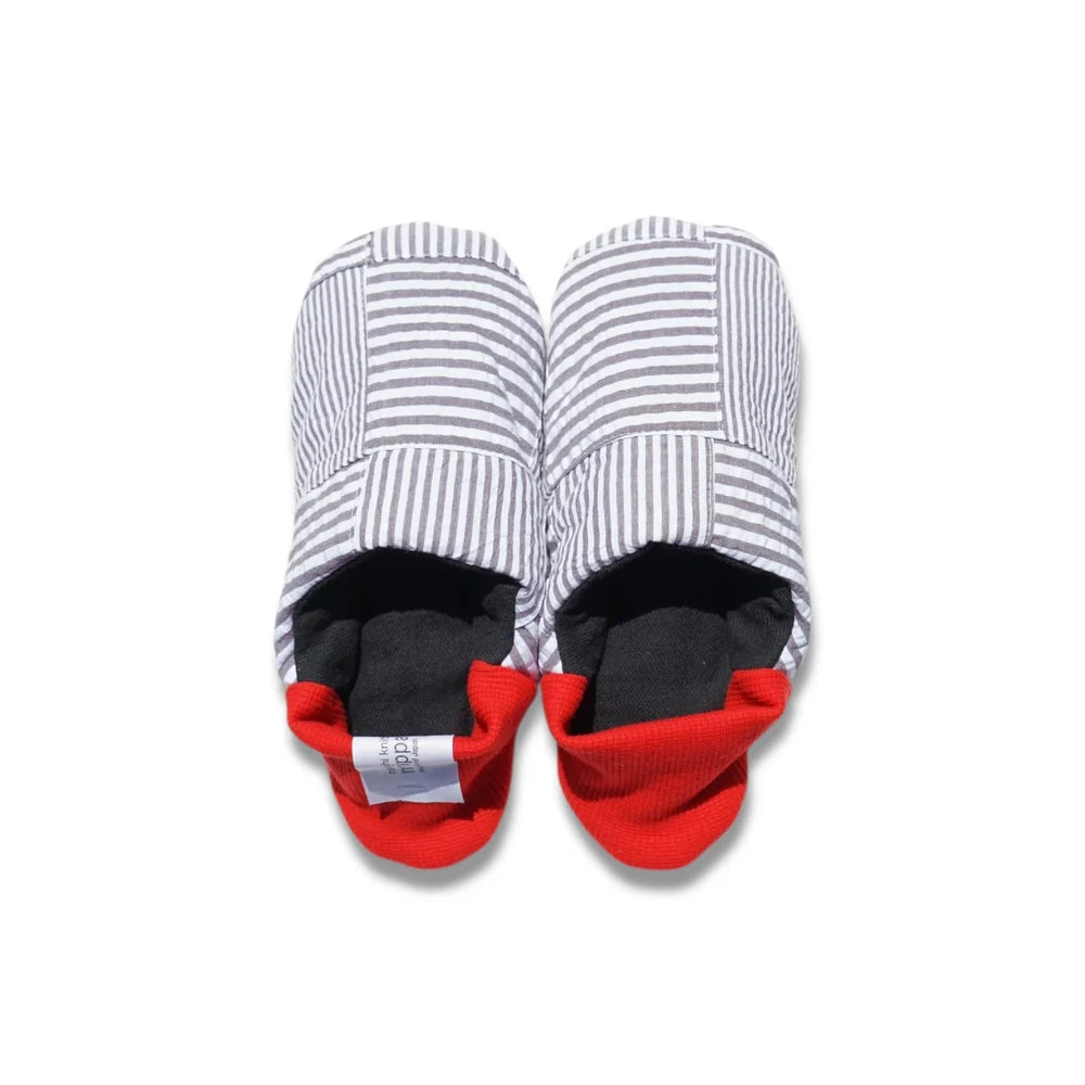 Pair of grey striped slippers with red heels on a white background