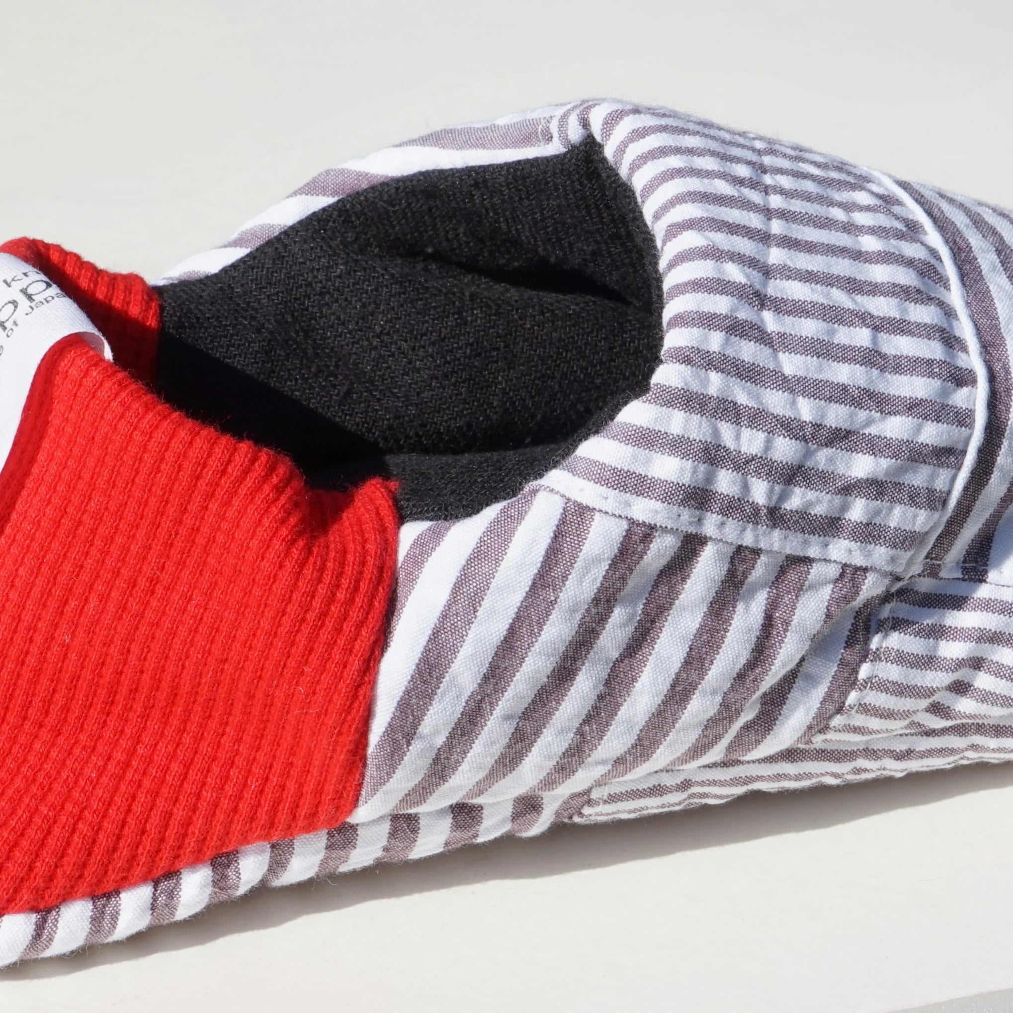 Close up of grey striped slippers with red heels on a white background