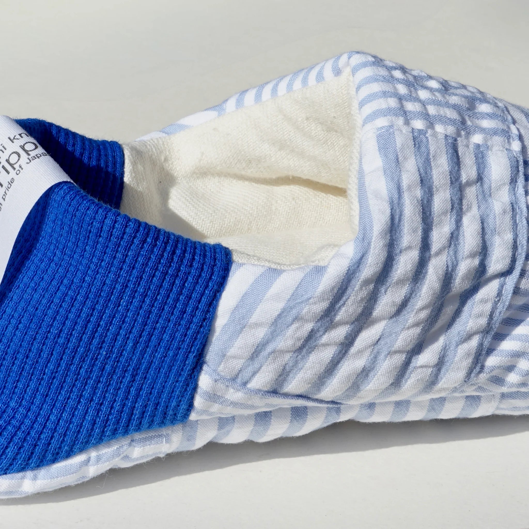 Close up of blue and white striped slippers with blue heels on a white background