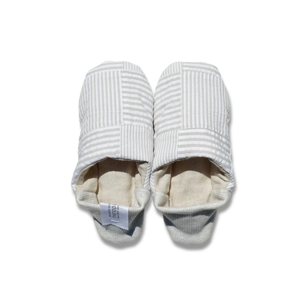 Pair of beige and white striped slippers on a white background