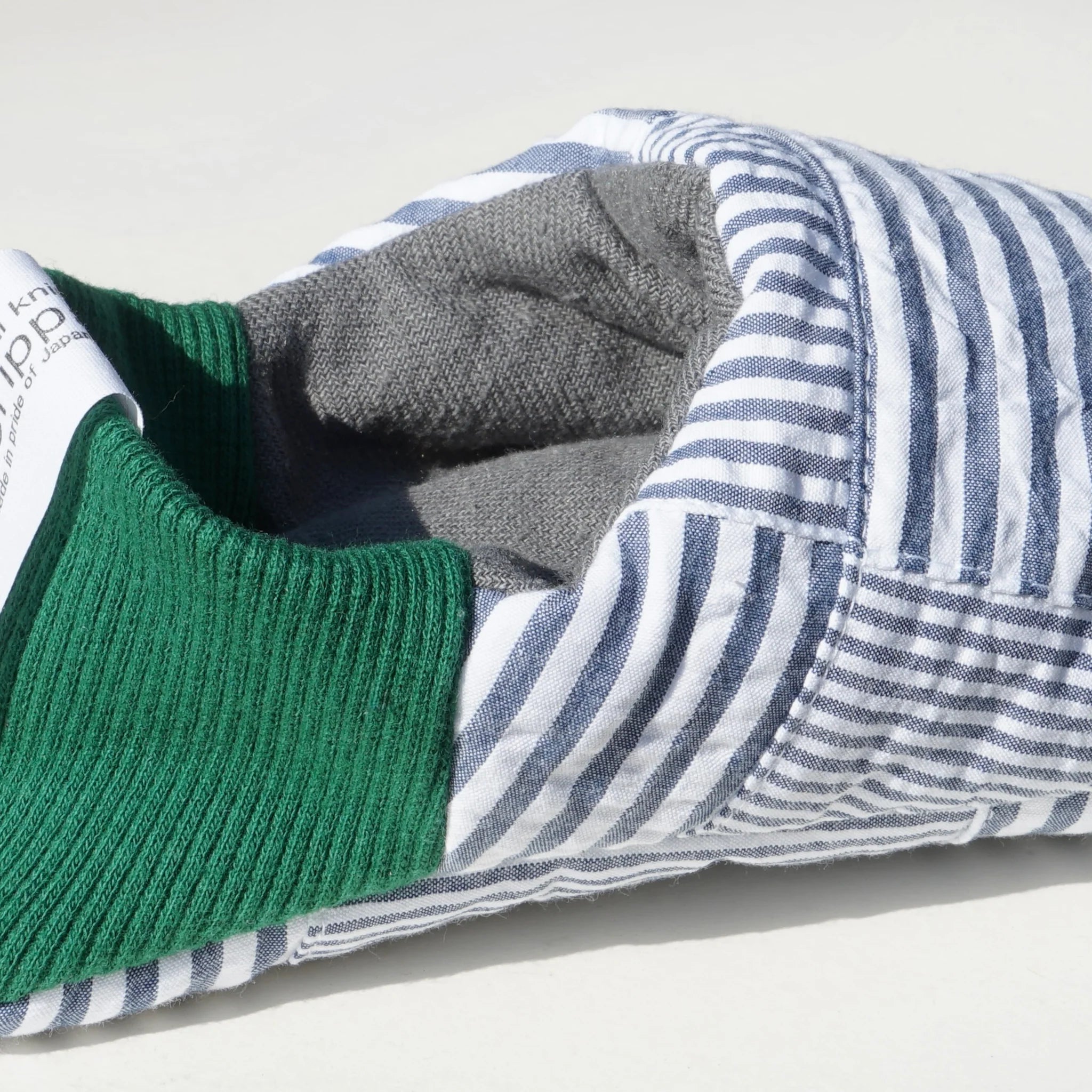 Close up of blue striped slippers with green heels on a white background