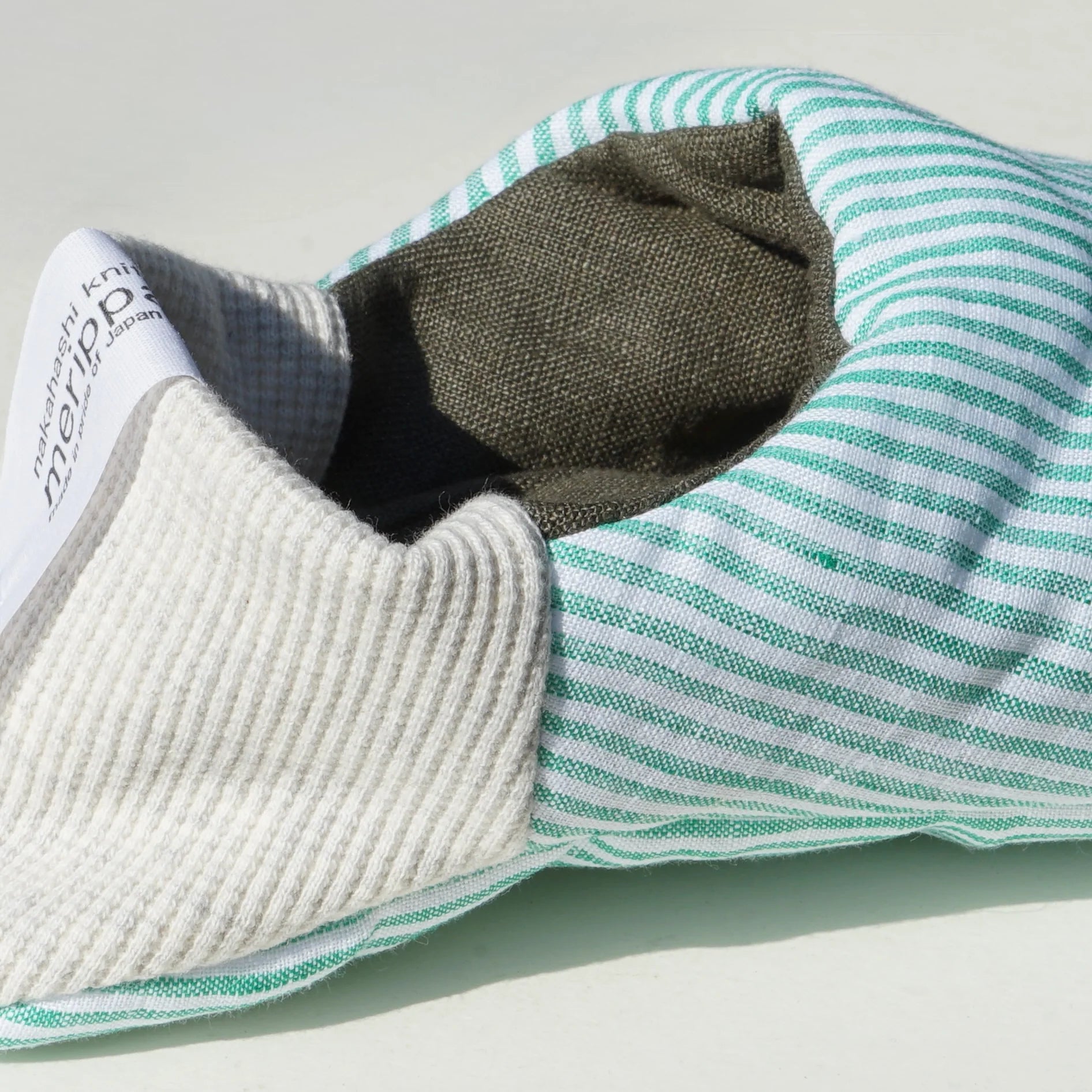 Close up of mint green and white striped slippers with light grey heels on a white background