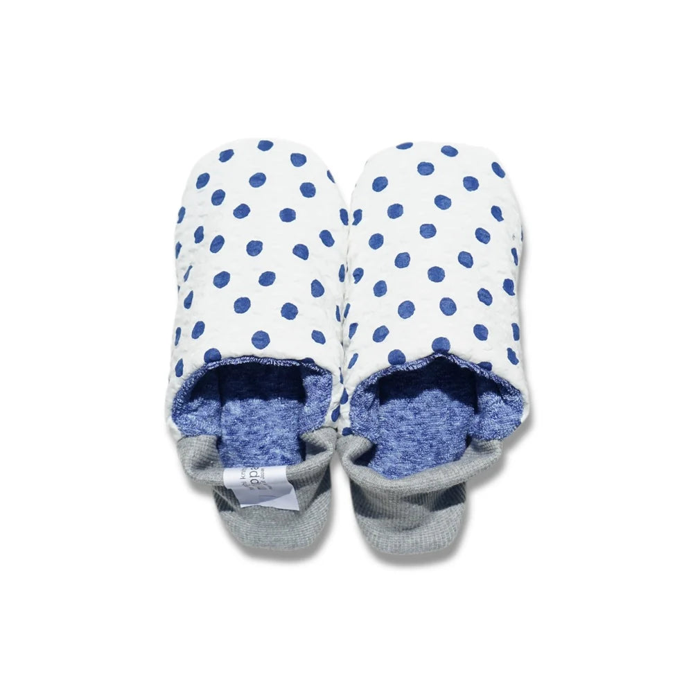 Pair of blue and white polka dot slippers with blue interior and gray heels on a white background