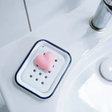 Heart-shaped pink soap on a white soap dish in a bathroom sink.