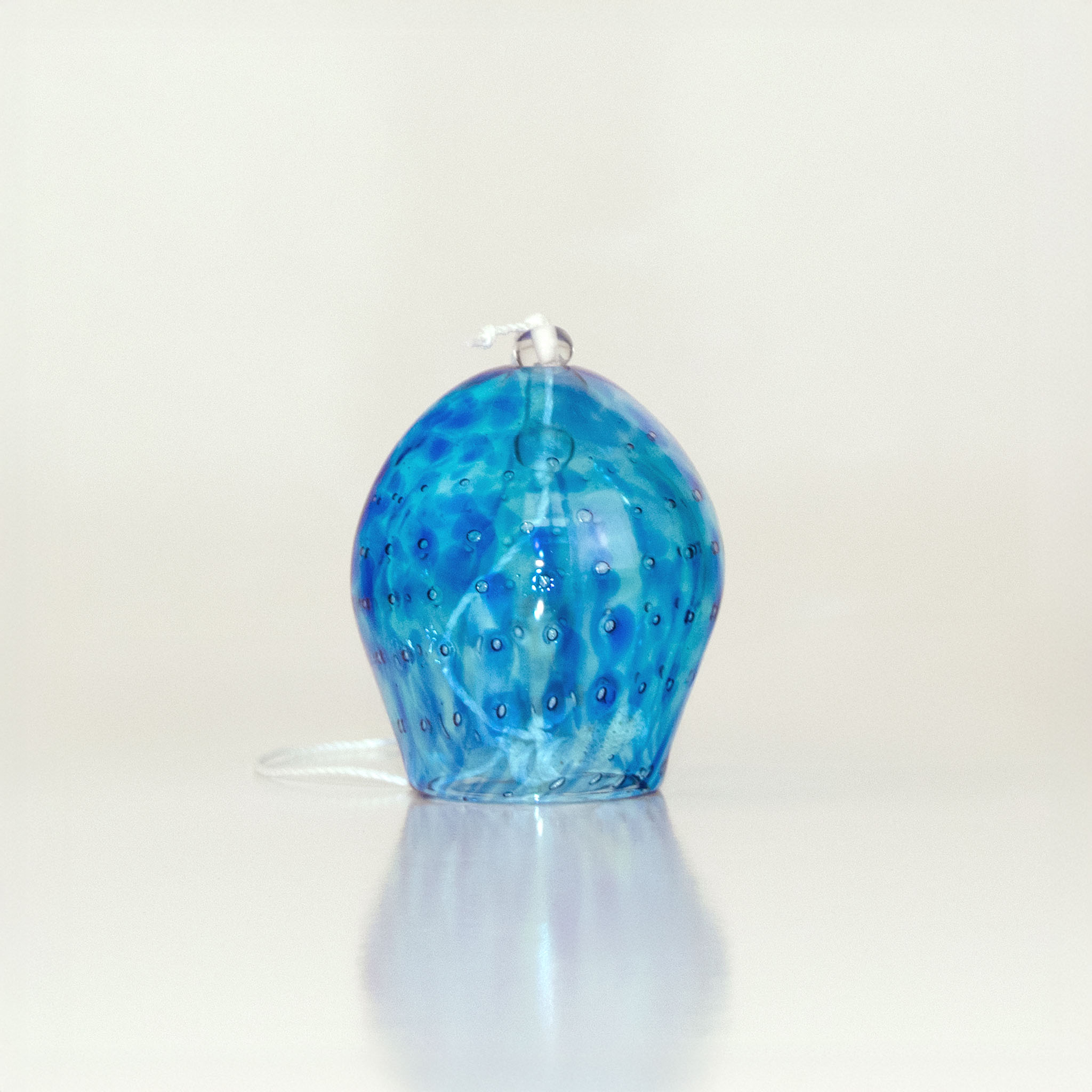 Blue handblown glass wind chime with textured surface on a white background
