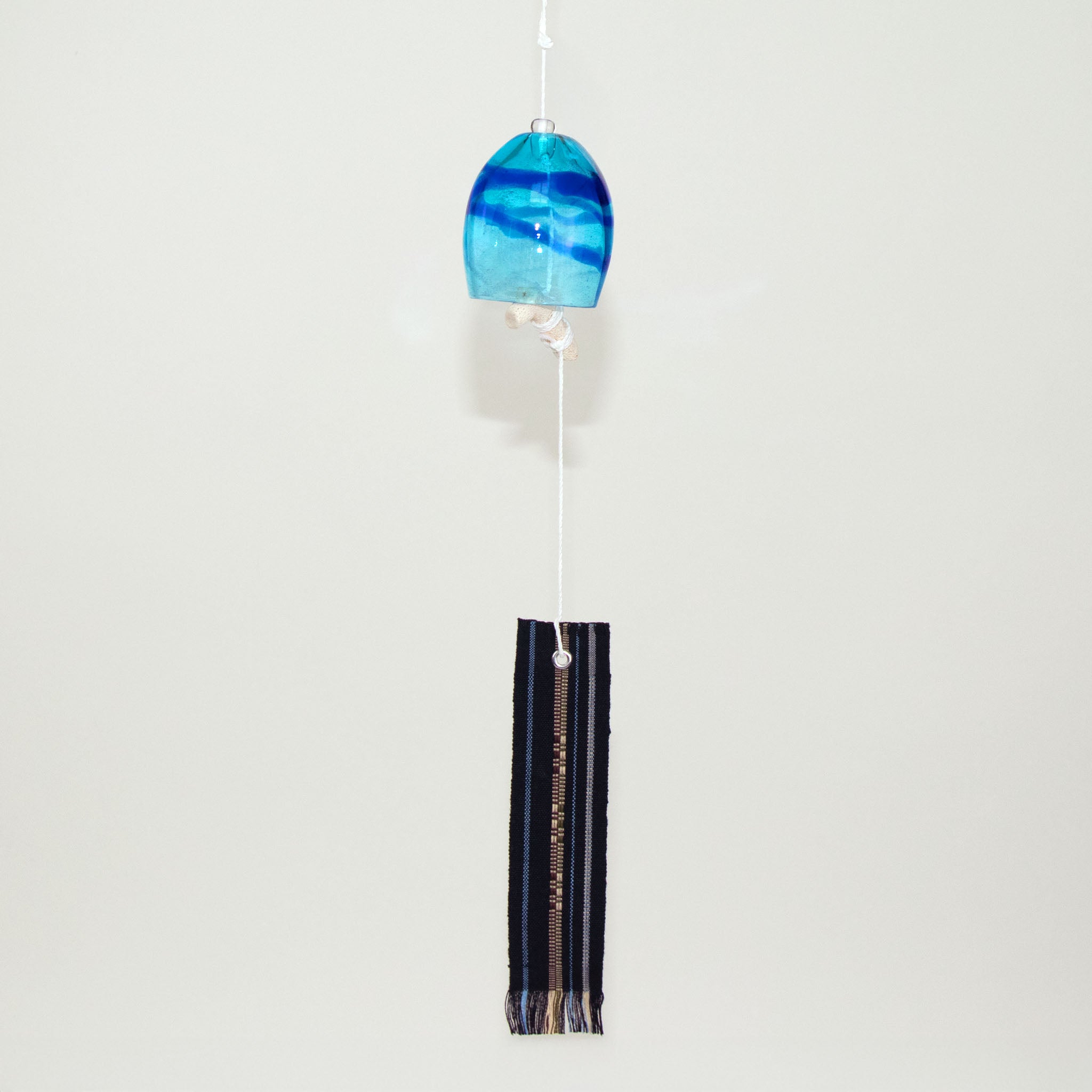  Blue glass Okinawan wind chime with black handwoven tab by Miyahira Studio, suspended on a white background.