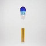 Blue glass Okinawan wind chime with yellow handwoven tab by Miyahira Studio, suspended on a white background.