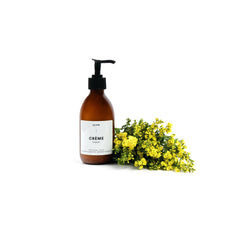 A bottle of La Vie's Bergamot Clementine placed next to a bunch of yellow wild flowers