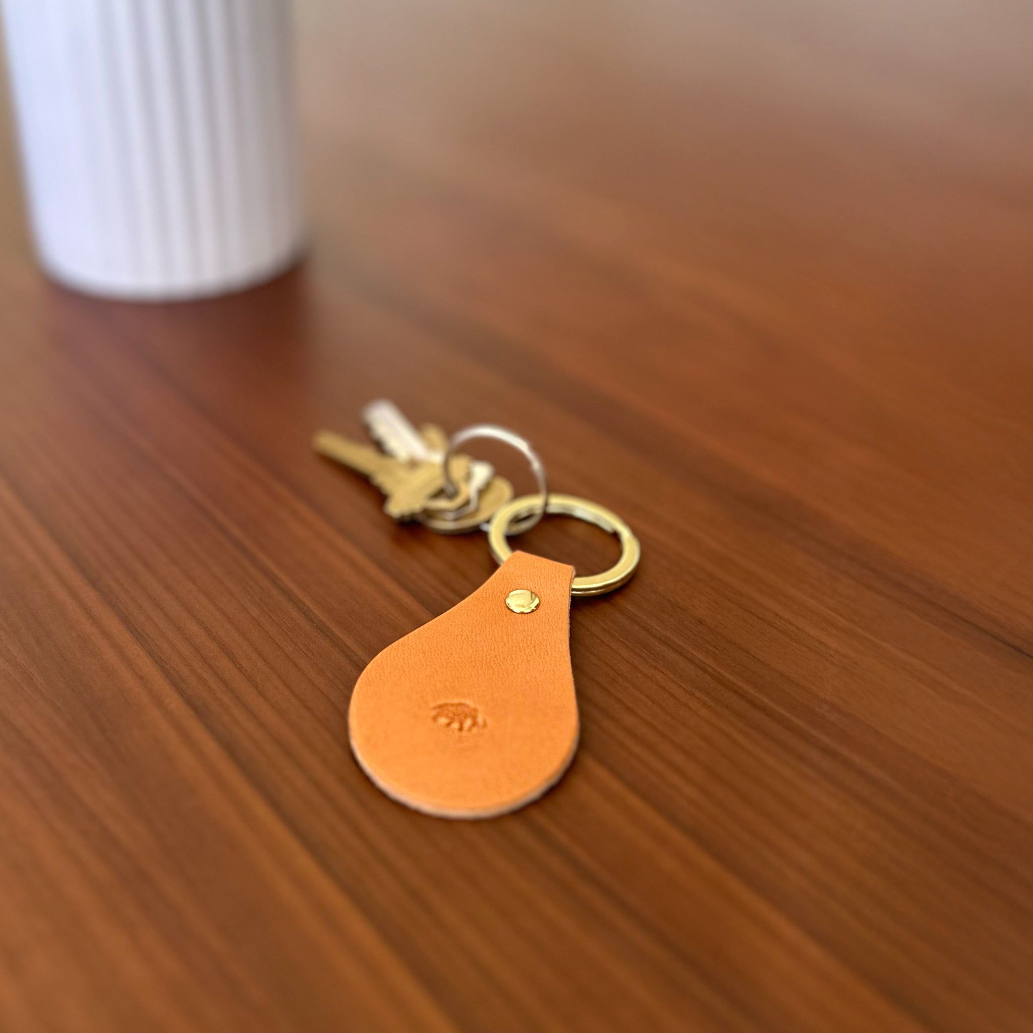 Orange leather keychain with keys on a wooden surface