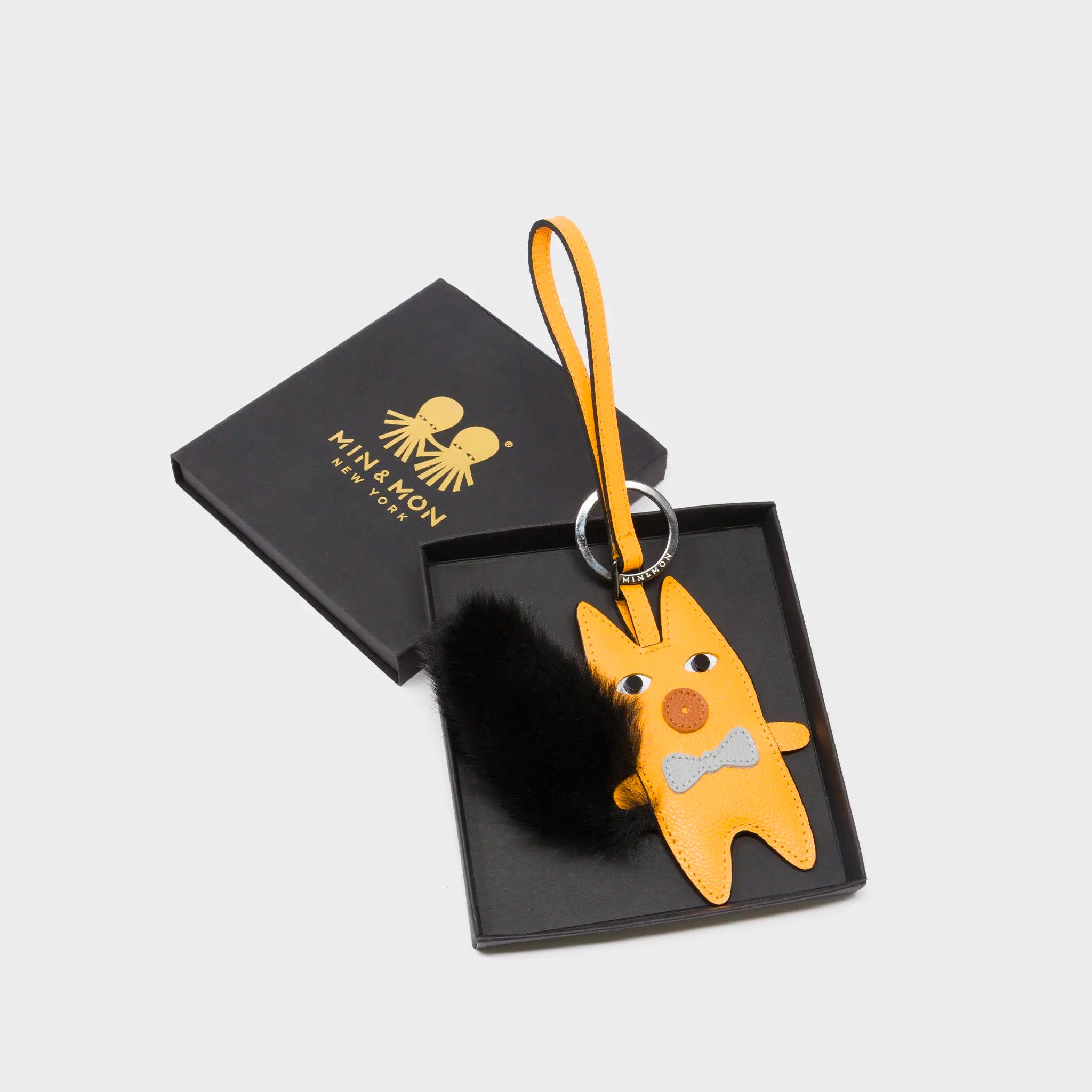 Min & Mon's Flufftail - Black and Marigold Leather Bag Charm in its retail packaging