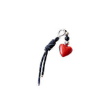 Red heart-shaped charm on a black cord against a white background