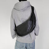 Person wearing a gray hoodie with hmhy's black buddy bag over one shoulder on a white background