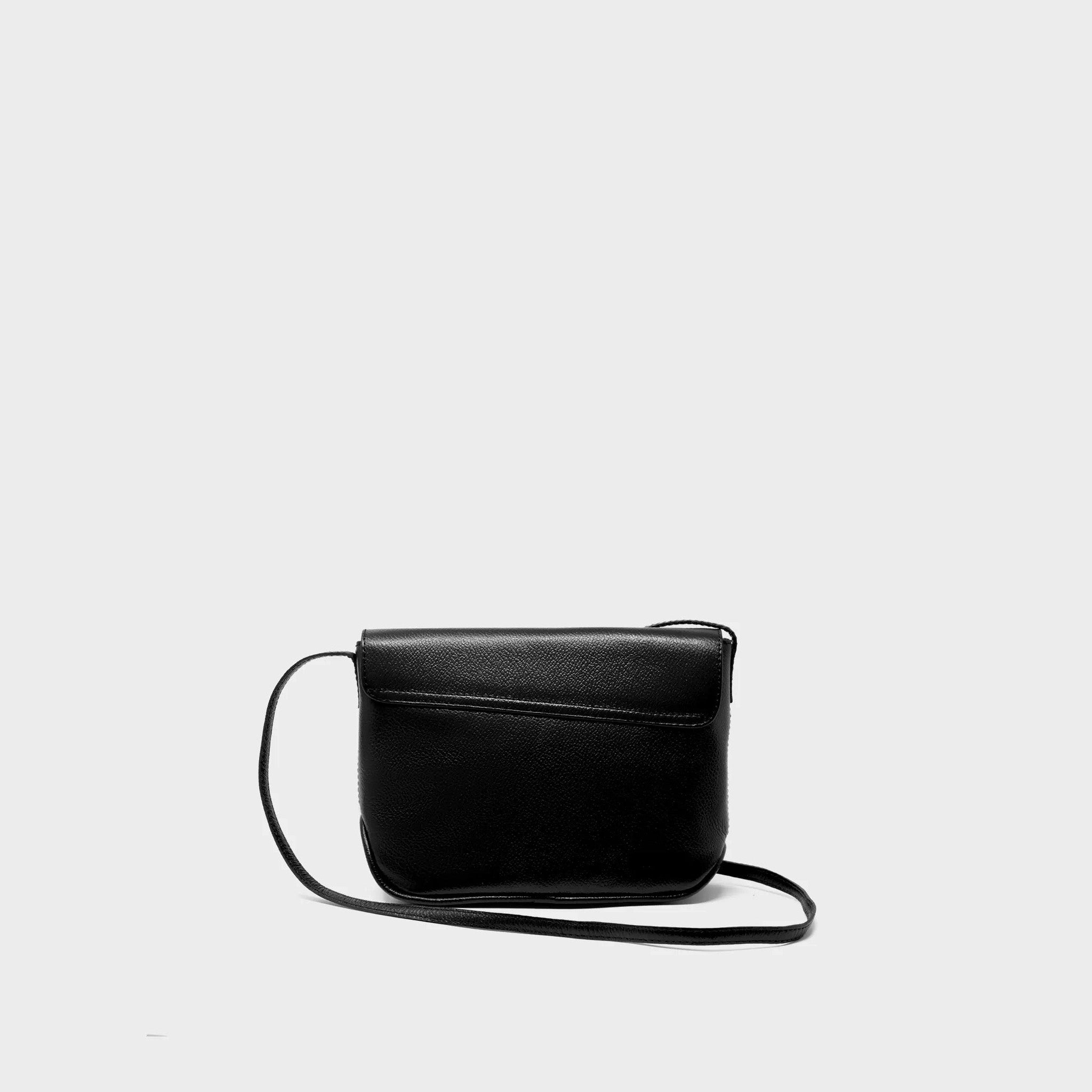 Back of the black leather crossbody bag with eye-shaped embroidery on a light gray background