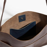 Close-up of a brown mini bonarda tote with blue interior lining and visible brand logo.