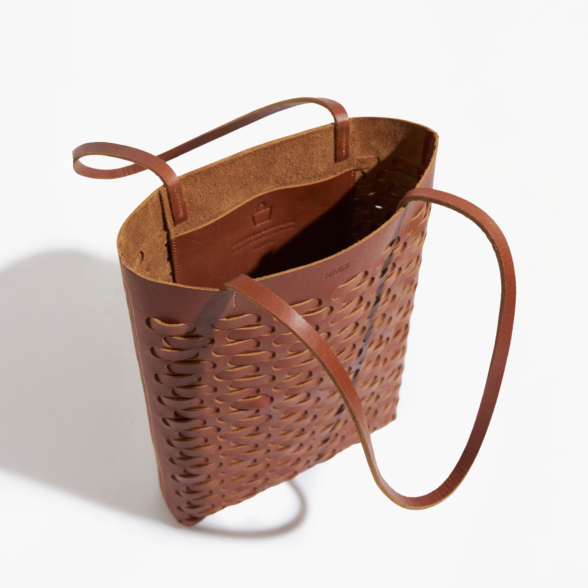 Brown leather weave tote bag with woven pattern on a white background