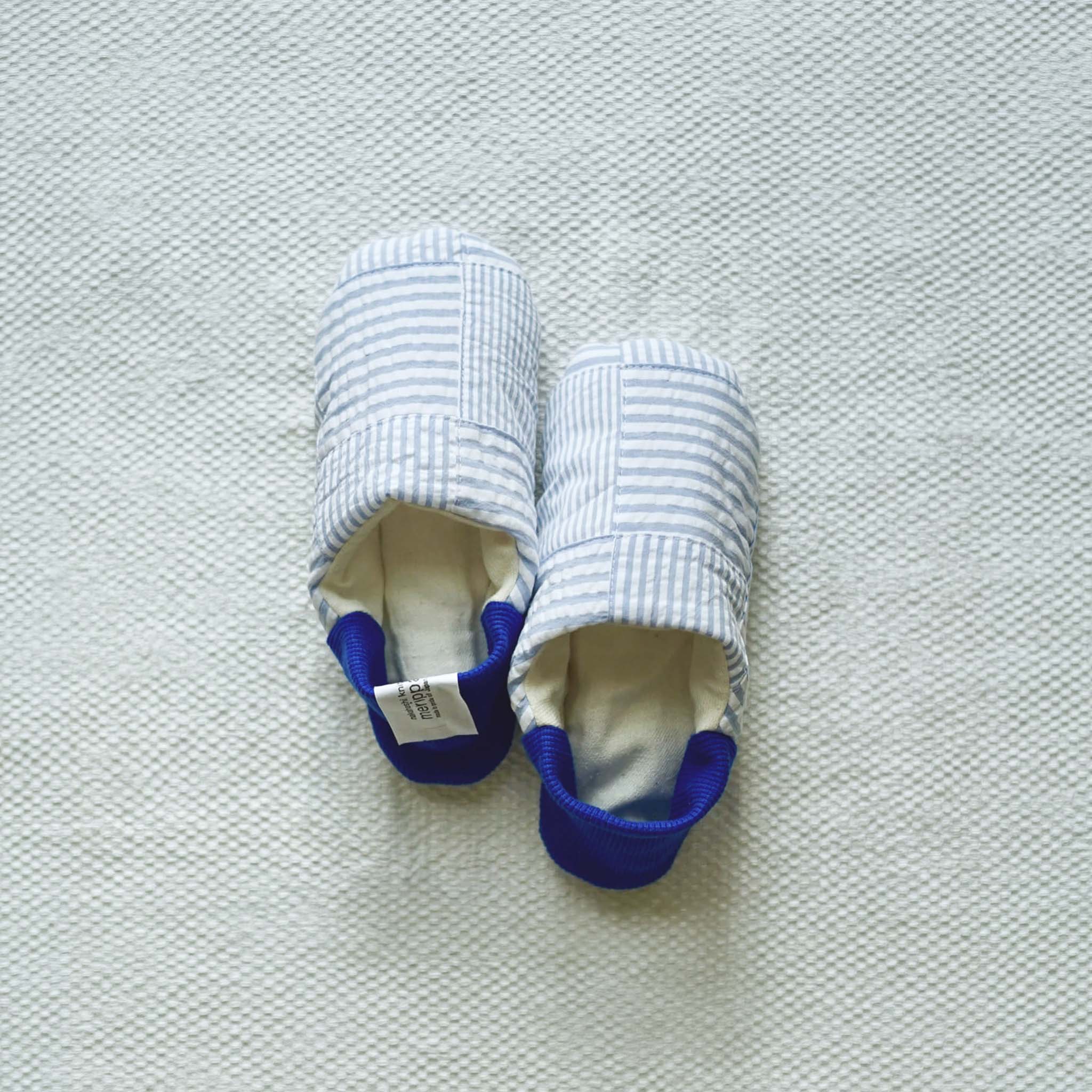 A pair of Merippa blue and white stripes with blue heels on a light gray textured background