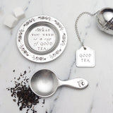 lifestyle image of beehive pewter tea scoop next to tea leaves and other items