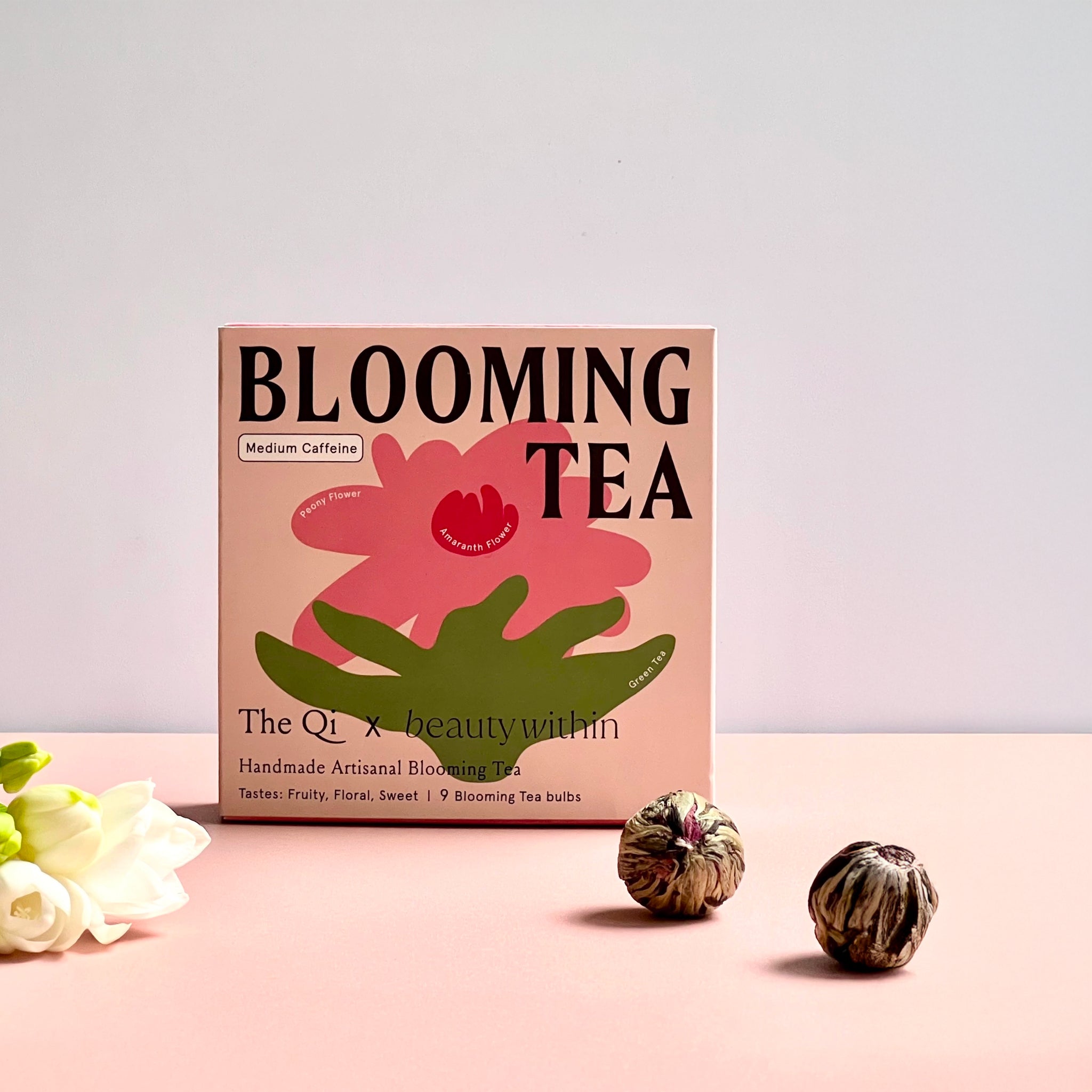 Box of Blooming Tea with blooming tea bulbs on a pink background