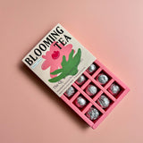 Box of Blooming Tea opened w bulbs wrapped on a pink background