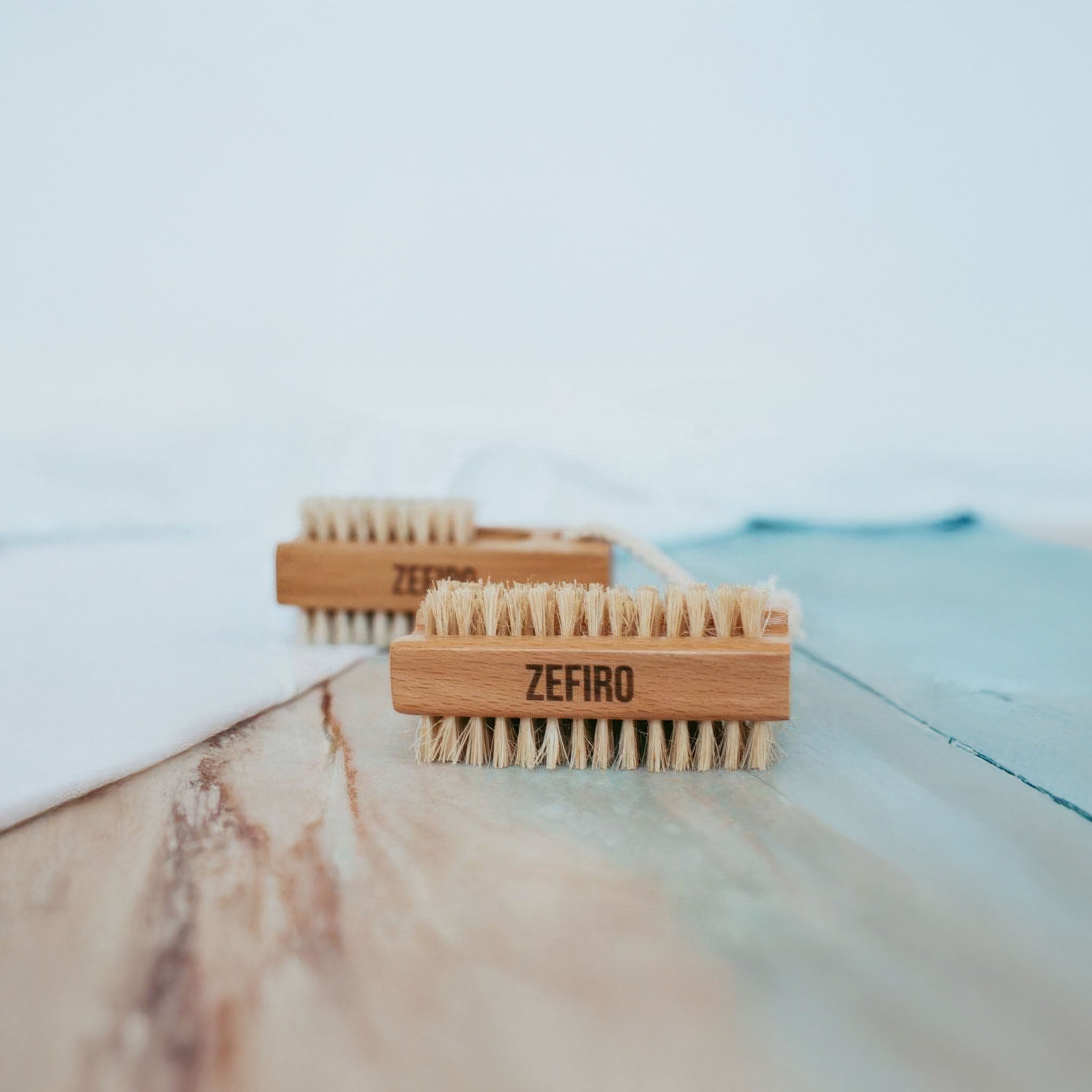 Two wooden brushes with bristle heads on a marble surface, branded 'Zefiro'.
