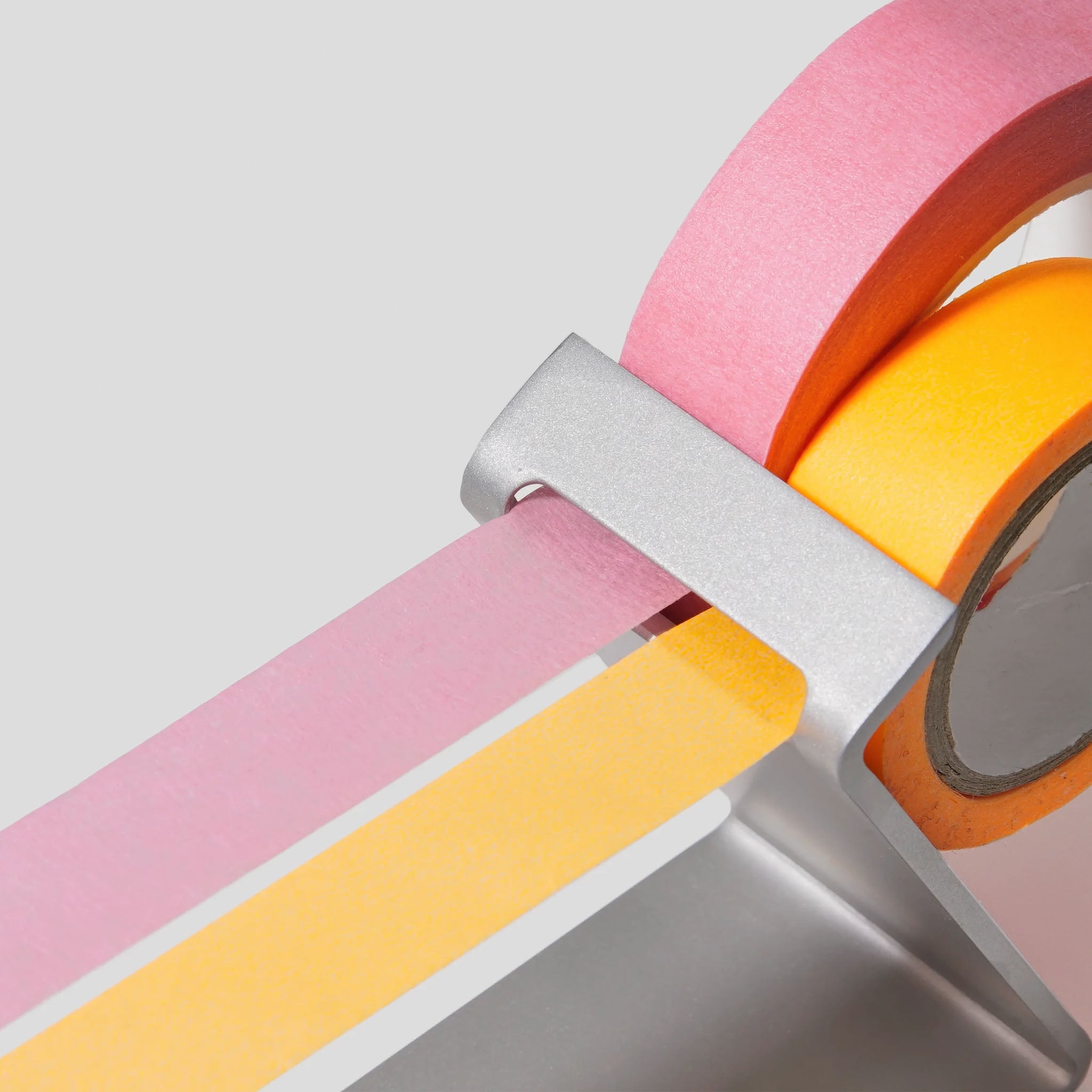 Close up of the Multi Radius Tape Dispenser holding rolls of orange and pink art tape.