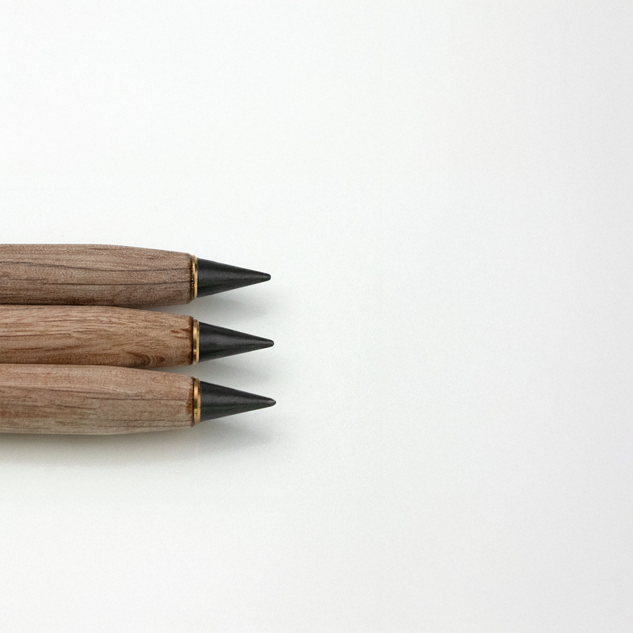 Three wooden pencils with black tips on a white background