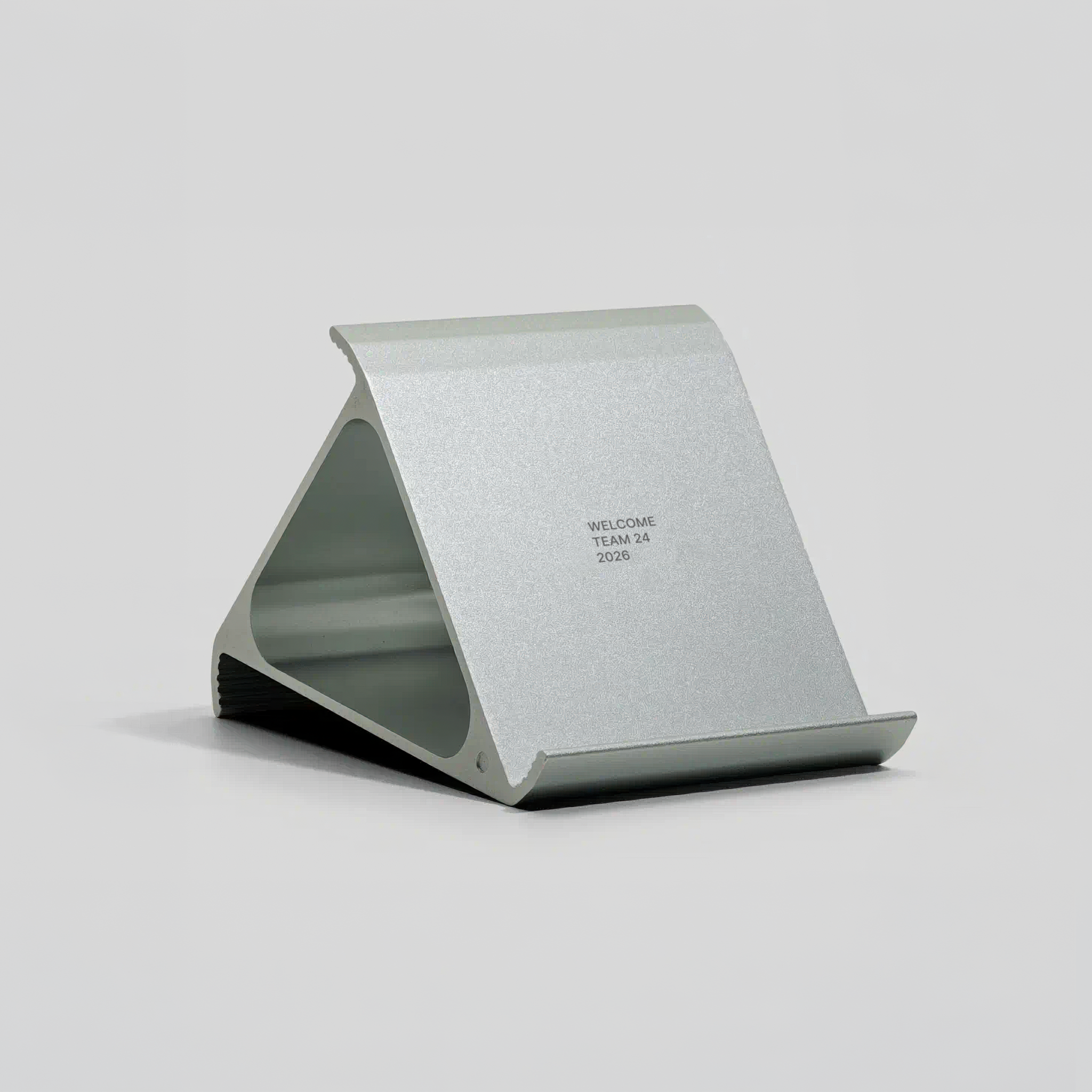 Silver metallic phone stand with custom engraving on a light grey background
