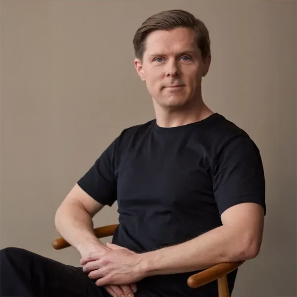 Designer Hans-Christian Bauer sitting in a chair wearing a black t-shirt against a plain background