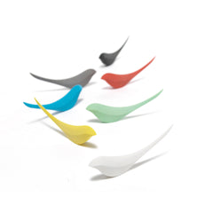 Colorful bird-shaped letter openers on a white branch against a white background