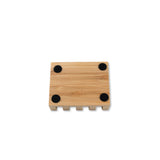 Displaying the underside of the slanted wooden soap dish with black circular pads on a white background