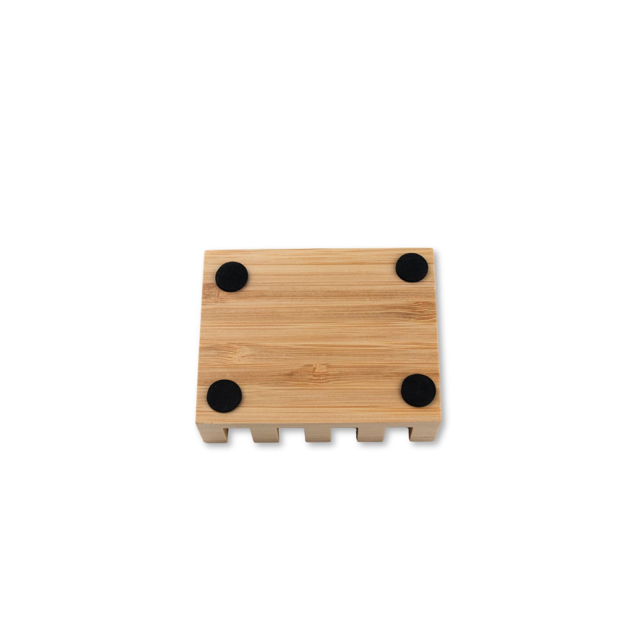 Displaying the underside of the slanted wooden soap dish with black circular pads on a white background